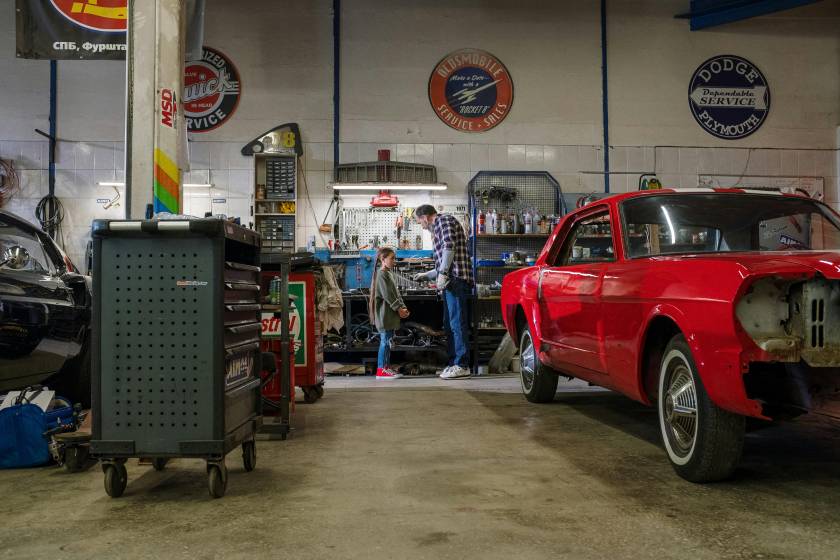 Grandfather and Granddaughter working in a car garage with red car